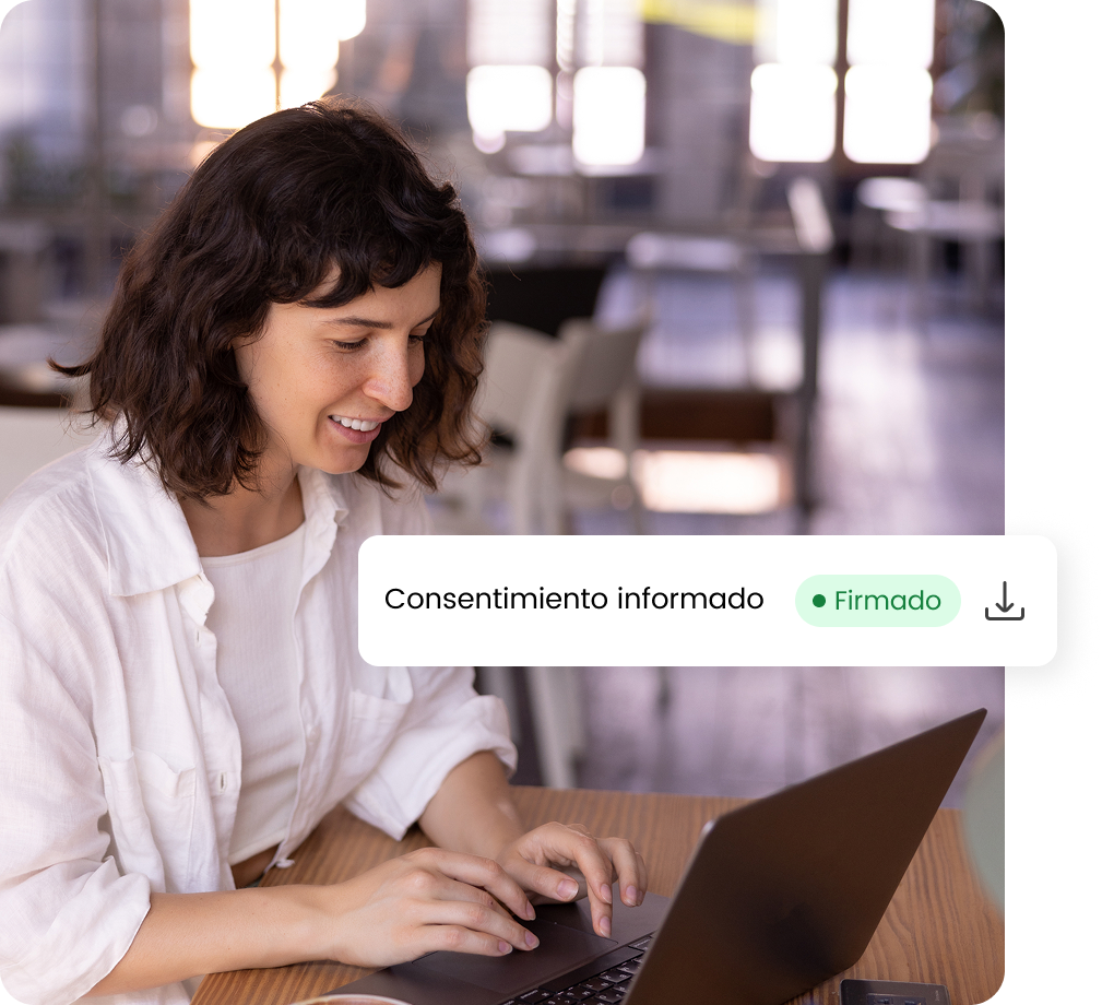 Mujer sonriente firmando digitalmente un consentimiento informado en su portátil en un ambiente de oficina.
