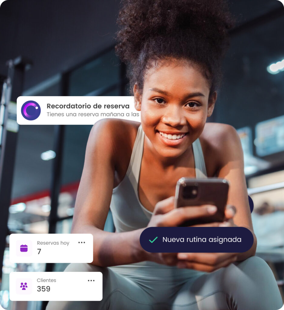 Mujer con smartphone en gimnasio revisa recordatorios de reservas y nueva rutina asignada en pantalla.
