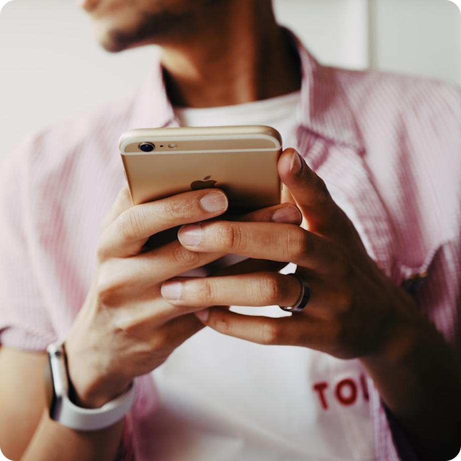 Usuario de teléfono móvil en camisa casual usando smartphone tecnológico dorado, vista de cerca de manos.