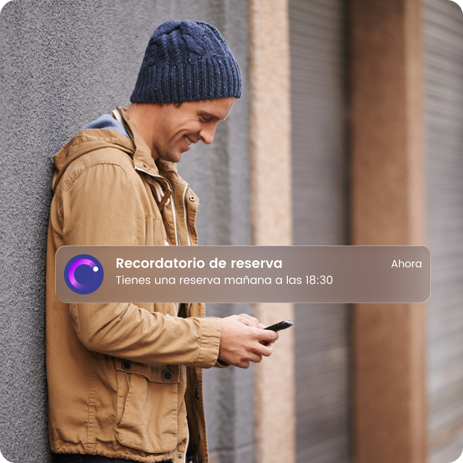 Hombre con gorro consultando su móvil, recibe notificación: Recordatorio de reserva mañana a las 18:30.
